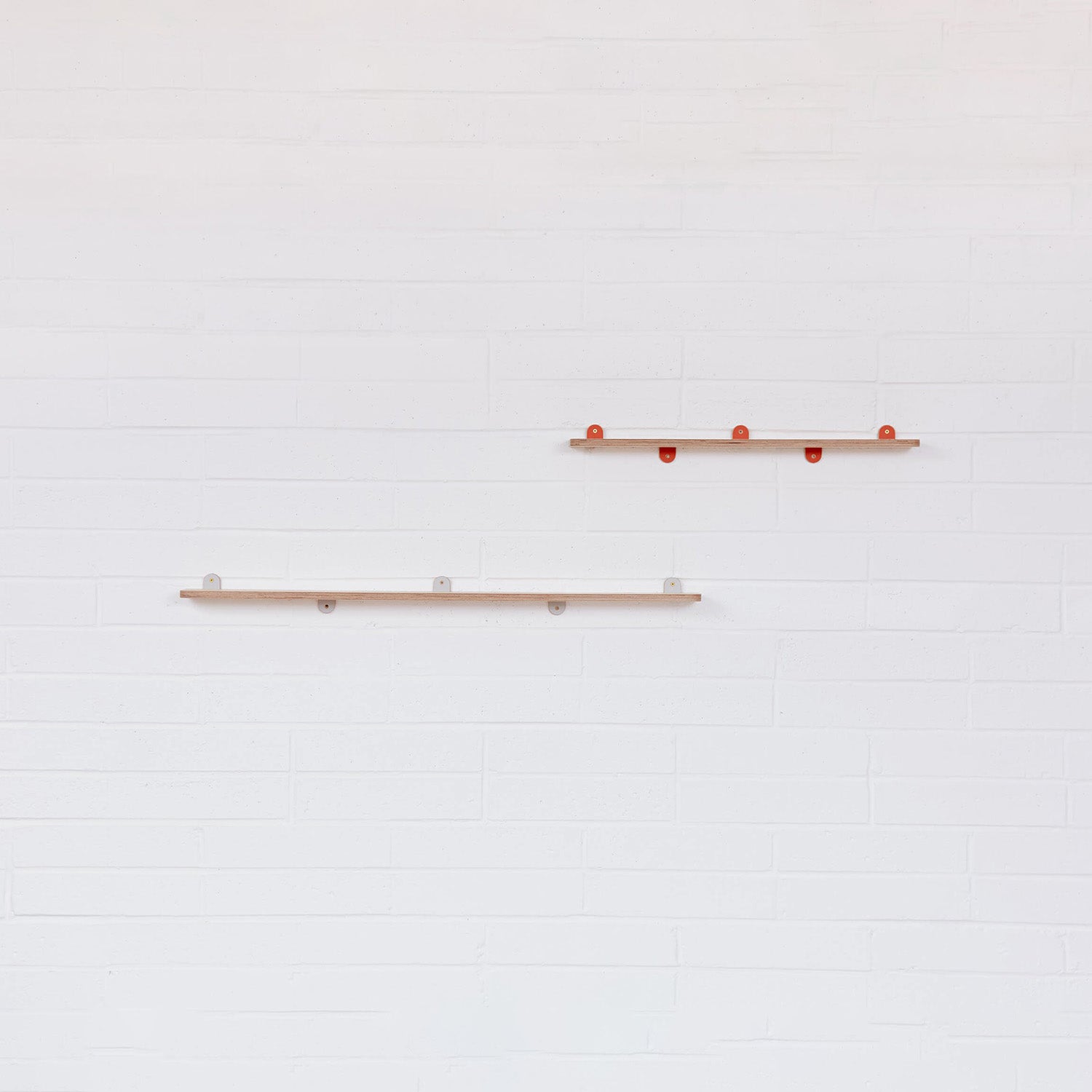 An empty pair of Lozi's plywood display shelves on a white brick background