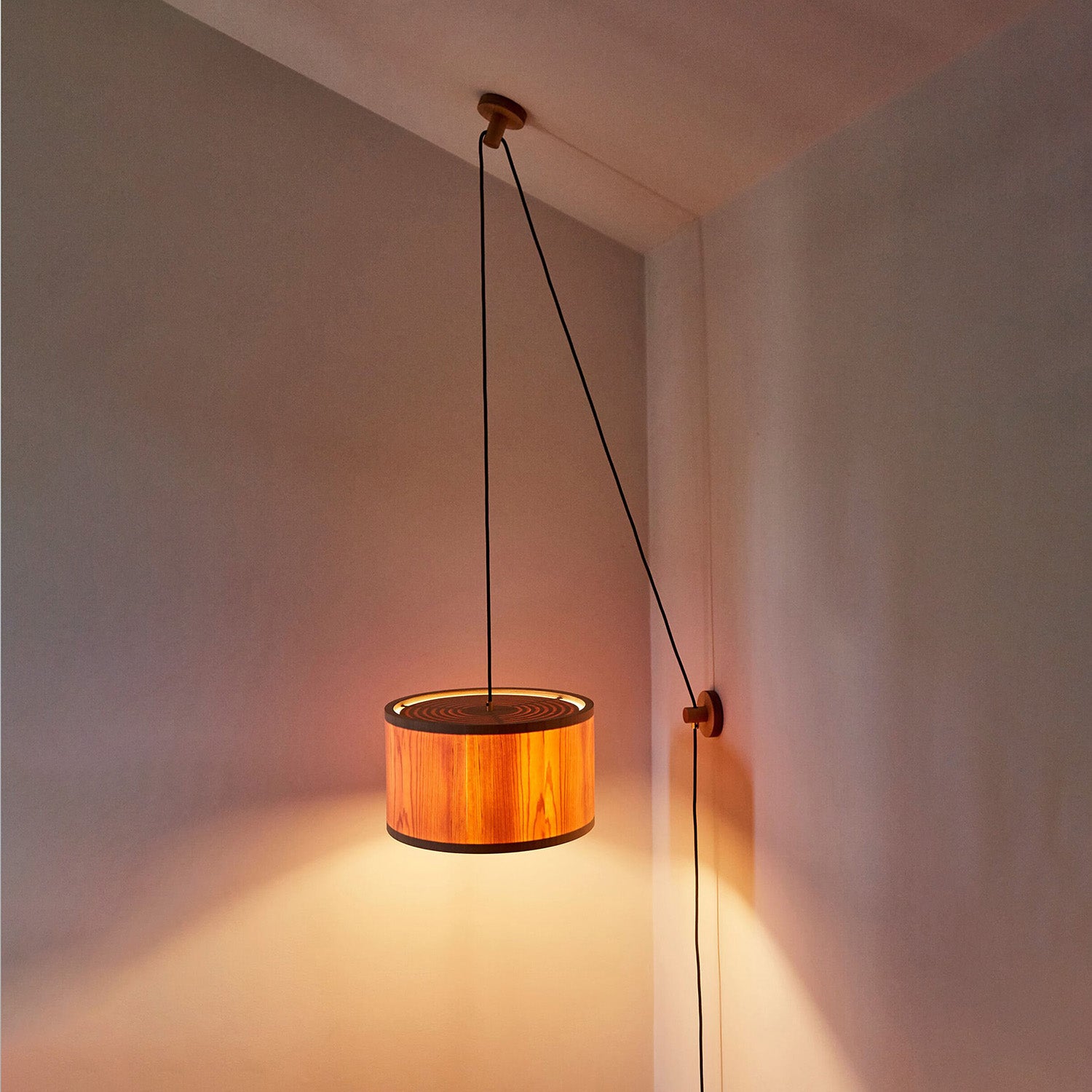Lozi's plywood and translucent wood veneer Round Lamp wall and ceiling mounted, turned on in a dark room